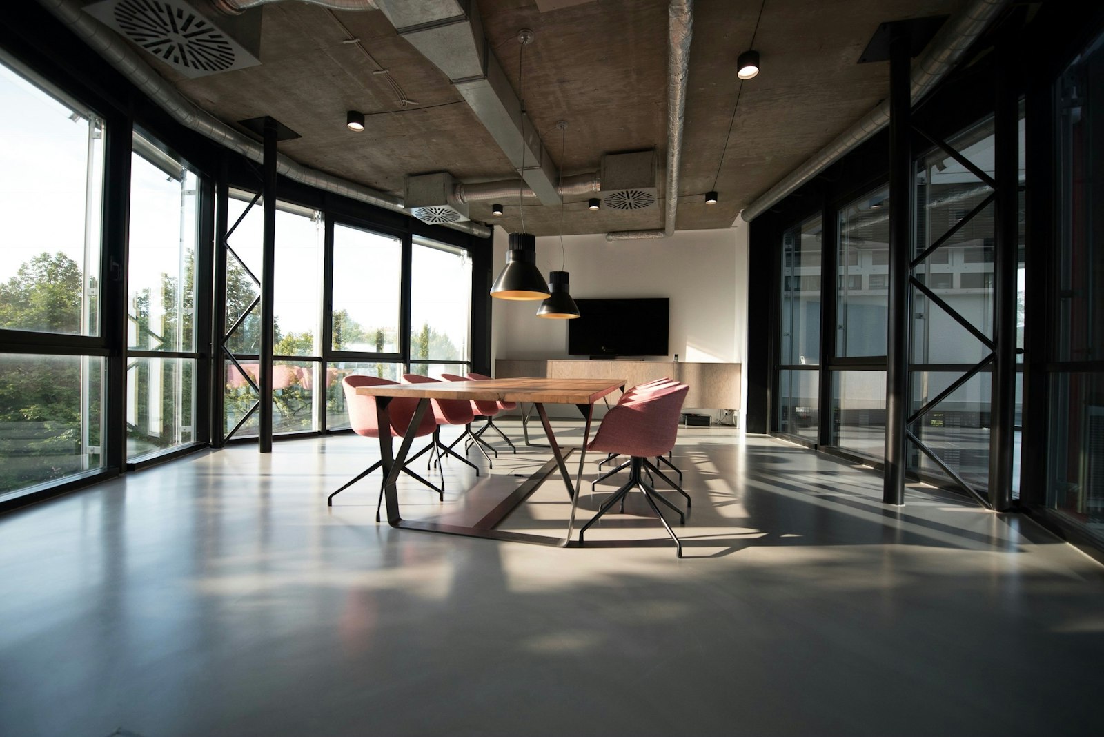 Modern office lounge with a conference table, glass walls, and open natural light